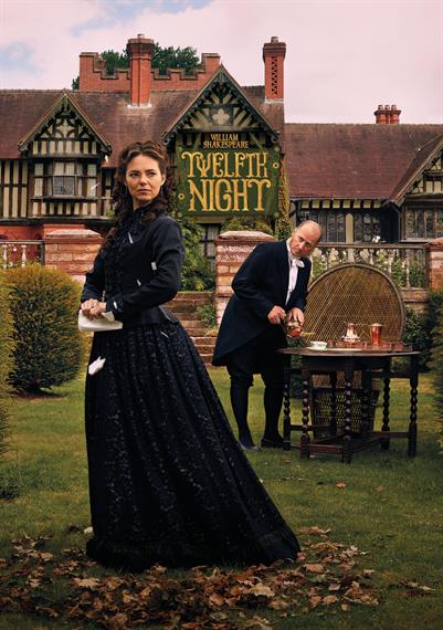 Proud woman in black Victorian dress stands in grounds of manor house waited on by steward who pours tea servant