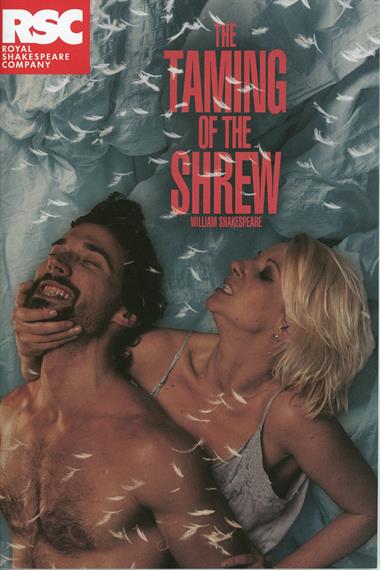 Theatrical programme cover for The Taming of the Shrew 2012 showing bare-chested man held by woman round chin in pillow fight